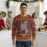 A man in a festive kitchen gathering wearing a brown Christmas sweater featuring a gingerbread character with integrated scannable QR code designs.
